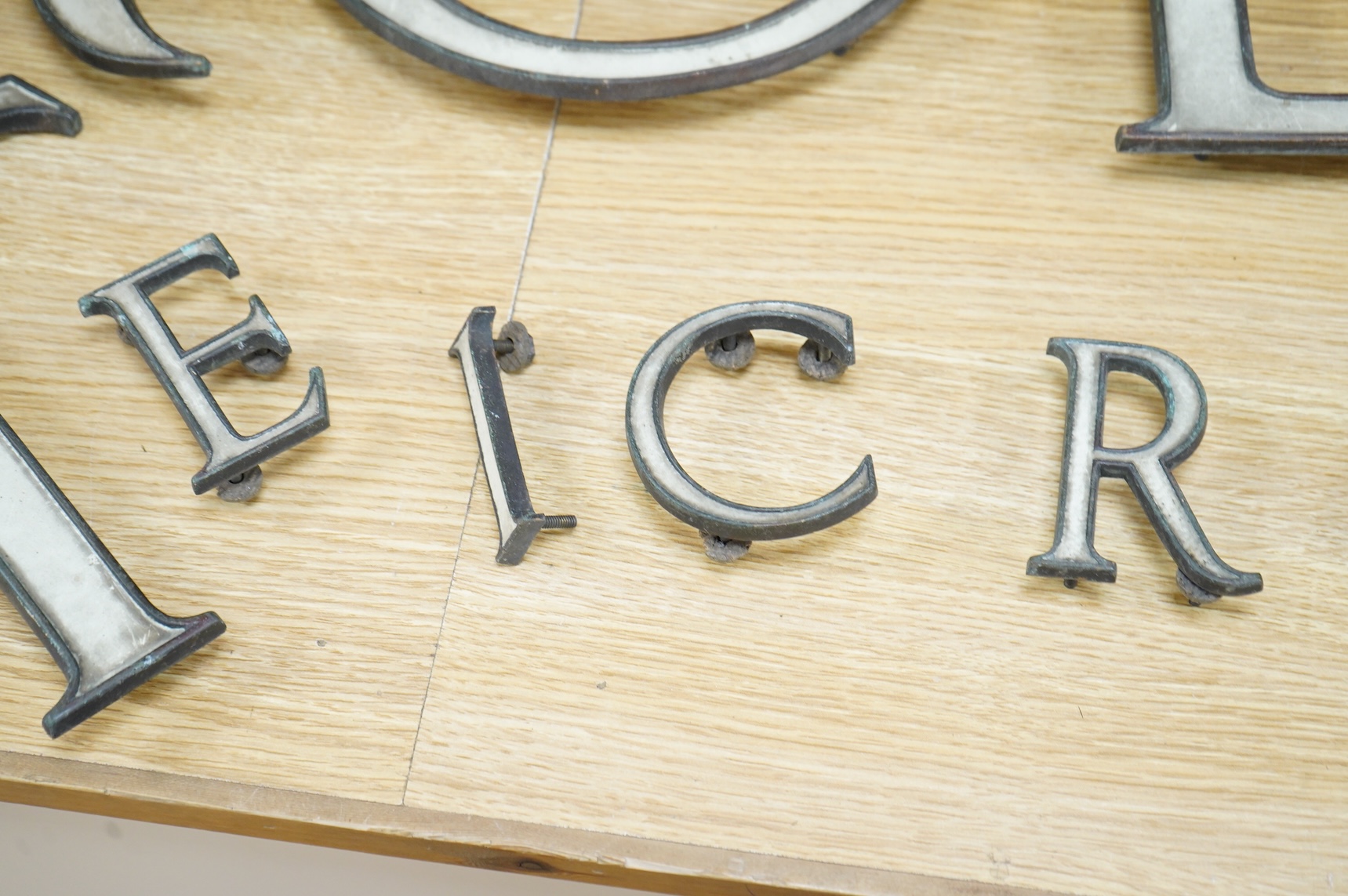 A part set of fifteen enamelled brass letters, largest 23cm